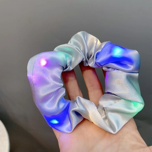 Close-up of LED glowing hair scrunchie made of shiny satin fabric with colorful lights