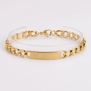 Macro detail of gold stainless steel bracelet featuring embossed Greek Meander patterns