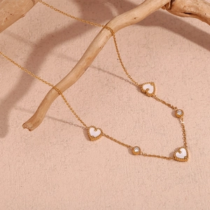 Detail of 18K gold-plated necklace featuring white heart pendants and round zircons