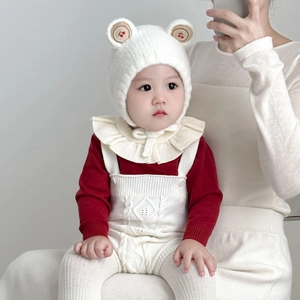 Détail du bonnet en tricot pour bébé avec oreilles d'ours et broderie cerise