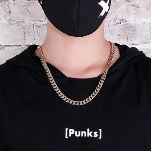 Gros plan d'un collier chaîne NK cubain bicolore or et argent porté par un mannequin