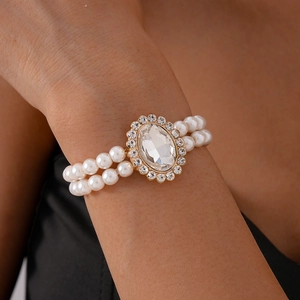Detailed close-up of double-layer pearl bracelet with oval crystal and gold finish