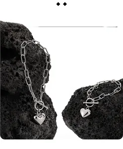 Detail view of silver heart pendant with paperclip chain and toggle clasp on volcanic rock