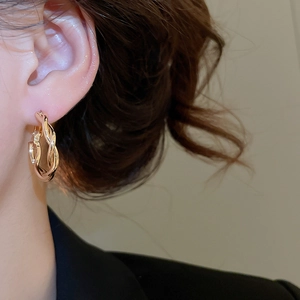 Nahaufnahme der goldenen gedrehten Creolen im minimalistischen Design an einem Model