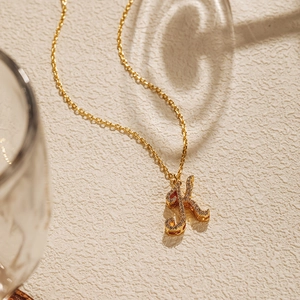 Detailed close-up of 18K gold-plated necklace featuring a pavé-set letter K pendant