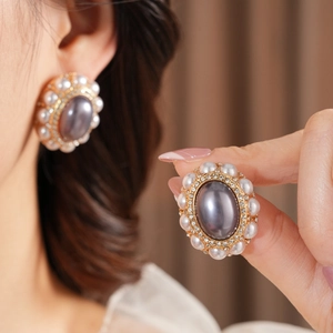 Detail view of vintage-style oval gray stone earrings with pearls and gold-tone base