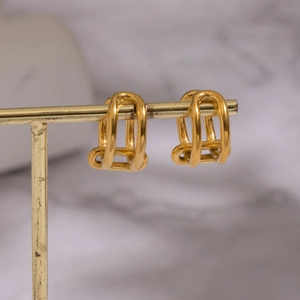 Minimalist gold geometric C-shaped ear cuffs on a stand with sleek multi-layer design