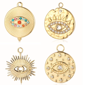 Gold evil eye pendants set with colorful crystals and sunburst pattern on white background