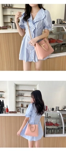 Detailed view of pink leather handbag with khaki straps worn in a cafe setting