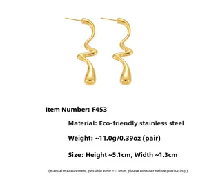 Détail de boucles d'oreilles en acier doré poli avec lignes courbes et goutte pendante