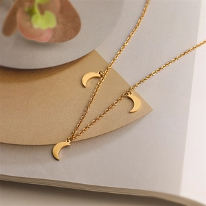 Detailed view of three gold moon pendants on a chain over minimalist beige card