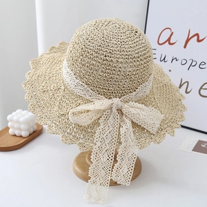 Detail of woven straw sun hat featuring elegant white lace ribbon and wavy brim design