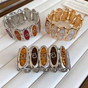 Detail view of elastic oval links bracelets with colorful enamel and geometric patterns