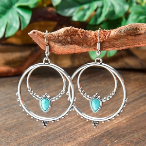 Macro detail of Bohemian teardrop turquoise earrings hanging on vintage wood branches