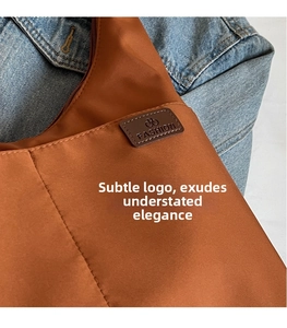 Detail of caramel canvas tote showing leather logo patch and fine fabric texture