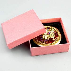 Macro detail of a vintage bronze floral makeup mirror with colorful crystals in a gift box