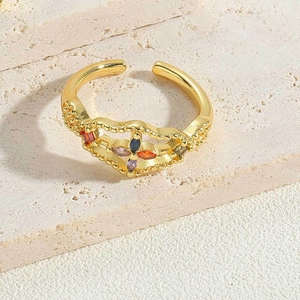 Macro detail of gold open ring with colorful zircon floral design on stone surface