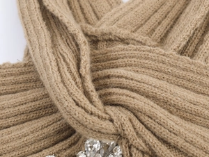 Macro detail of camel knit cardigan fabric texture with sparkling rhinestone embellishments