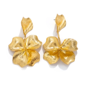 Macro view of golden metallic leaf earrings with textured petals and brushed finish
