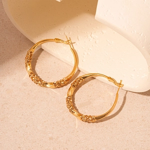 Macro view of gold-plated twisted hoop earring featuring amber crystal pavé detailing