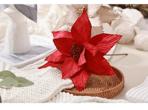 Gros plan d'un poinsettia artificiel en velours rouge avec paillettes sur un plateau tressé