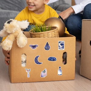 Child by moving box decorated with purple celestial moon and butterfly stickers