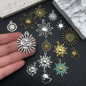 Detailed view of assorted sun-shaped alloy charms in silver and bronze on black leather