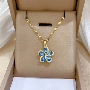 Macro detail of rotating blue flower necklace with rhinestones and gold-plated chain