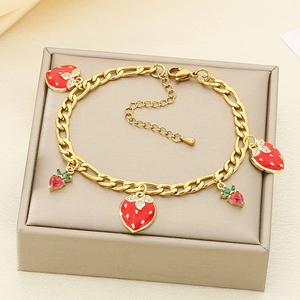 Detailed macro view of strawberry enamel charms on a gold-plated titanium steel bracelet