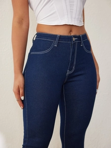 Detail view of high-waist dark blue jeans with contrast white stitching and cotton texture