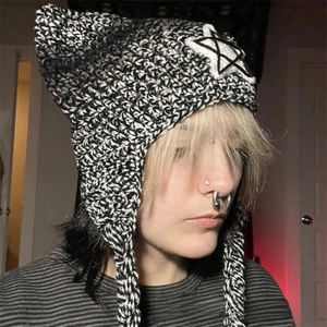 Detail of hand-knit cat ear beanie with star patch and striped tassels in black and white