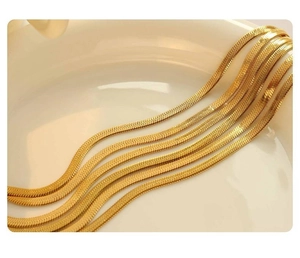 Dettaglio macro di catene a serpente placcate in oro 18K su un piatto di ceramica bianca
