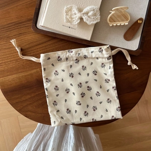 Detailed top view of a vintage floral cotton drawstring pouch on a dark wooden table