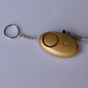 Detail view of gold egg-shaped personal security alarm with LED light and keychain