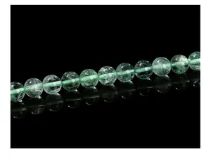 Macro view of round green fluorite beads with natural ice cracks on black mirror