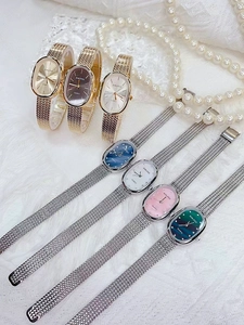 Close-up of elegant oval quartz watches with metallic mesh bands and various dial colors