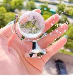 Close-up of a rotating crystal globe with silver metal stand held in hand