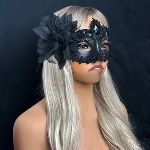 Close-up of black masquerade mask featuring delicate lace, beads, and side mesh flower