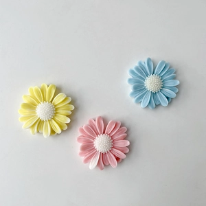Close-up of colorful resin daisy flowers in yellow pink and blue on white background
