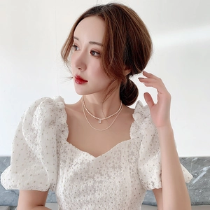 Close-up of double-layer pearl necklace with a square diamond pendant on floral clothing