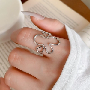 Macro d'une bague nœud minimaliste en argent portée au doigt sur un fond esthétique
