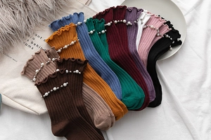 Detail of ribbed knit socks with pearl bead accents and elegant ruffled lettuce edge cuffs