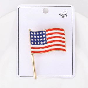 Detail shot of a wavy US flag enamel brooch pin with a gold finish on white card