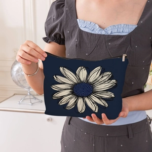 Blue canvas daisy pattern makeup bag with zipper held by a model in a white room