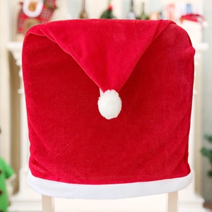 Detail of red velvet Christmas chair cover with white plush pom-pom in festive home setting