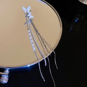 Detailed view of silver butterfly ear cuff with tassels and pearls on black reflective base