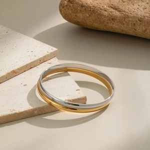 Elegant gold and silver dual-tone stainless steel bracelets on stone display
