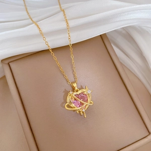 Detailed shot of gold necklace with pink heart gemstone pendant on beige jewelry box