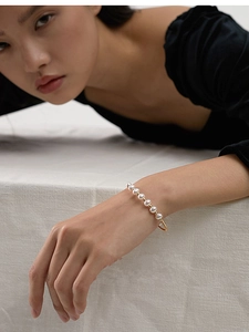 Detail of handcrafted gold wire wrapped pearl bracelet on female wrist with elegant finish