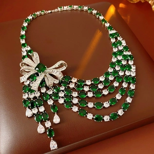 Détail du collier multicouche avec gemmes ovales vertes et pendentif noeud brillant